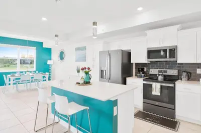 a kitchen with white cabinets and a blue island at Modern Storey Lake Resort Disney Orlando 3191-103 in Kissimmee