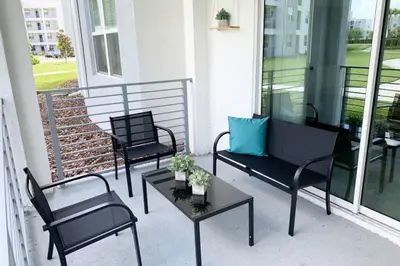 a porch with three chairs and a couch and a table at Modern Boho Storey Lake Resort Disney 3150-106 in Kissimmee