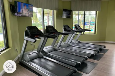 a row of treadmills in a gym with windows at Modern Storey Lake Resort Disney Orlando 3141-103 in Kissimmee