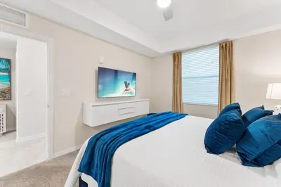 a white bedroom with a large bed with blue pillows at Modern Storey Lake Resort Disney Orlando 3171-302 in Kissimmee