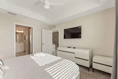 a white bedroom with a bed and a flat screen tv at Modern Storey Lake Resort Disney Orlando 3171-304 in Kissimmee