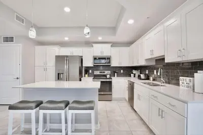 a white kitchen with white cabinets and bar stools at Modern Storey Lake Resort Disney Orlando 3121-108 in Kissimmee