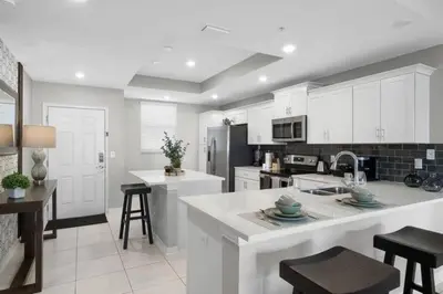 a kitchen with white cabinets and a kitchen island with stools at Modern Storey Lake Resort Disney Orlando 4741-104 in Kissimmee