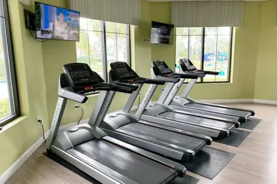 a row of treadmills in a gym with windows at Modern Storey Lake Resort Disney Orlando 3180-104 in Kissimmee