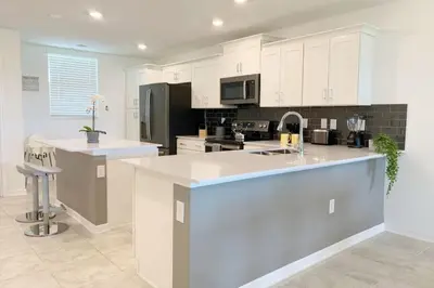 a kitchen with white cabinets and a large island at Modern Storey Lake Resort Disney Orlando 3191-204 in Kissimmee