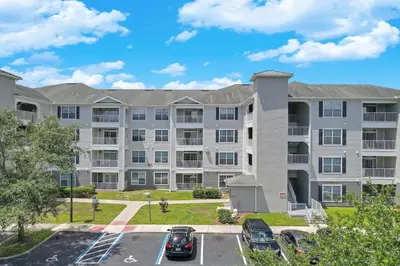 an apartment building with cars parked in a parking lot at Secret Lake Resort 3BR Apt Disney Orlando 3175-205 in Kissimmee
