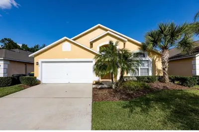 a house with palm trees in front of a driveway at Make your dreams really come true in Kissimmee