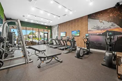 a gym with several treadmills and exercise bikes at MAGIC VILLAGE - Near Disney - 4BDR in Orlando