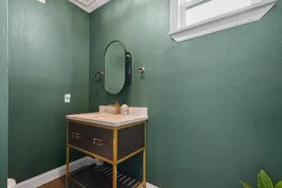 a bathroom with a sink and a mirror on a green wall at 5 Bdr 4,5 Bth Villa - Pool Table - Fenced Yard in Orlando