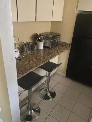 a kitchen with a counter with two stools and a microwave at Botanical Tranquility in Orlando