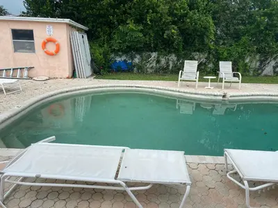 a swimming pool with two chairs and a table and chairs at Botanical Tranquility in Orlando