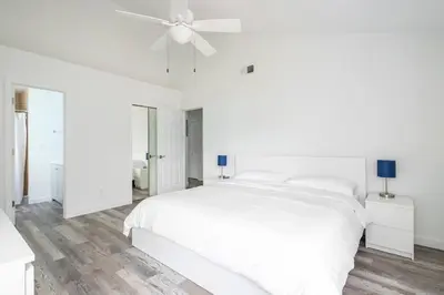 a white bedroom with a white bed and a ceiling fan at The Villa of Somerset in Kissimmee