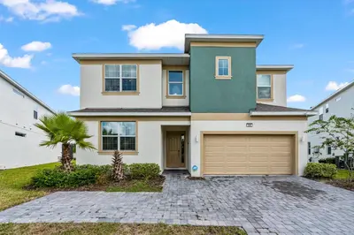 a house with a garage and a palm tree at Beautiful 12Bed11.5Bath House At Bella Vida in Kissimmee