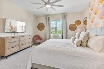 a white bedroom with a large bed and a dresser at Beautiful 12Bed11.5Bath House At Bella Vida in Kissimmee