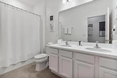 a white bathroom with two sinks and a toilet at Beautiful 12Bed11.5Bath House At Bella Vida in Kissimmee