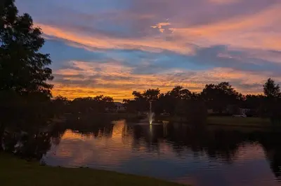 a sunset over a lake with a fountain in the middle at Smart home near Disney world, Silver Spurs Arena in Kissimmee