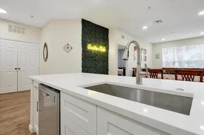 a white kitchen with a sink and a dining room at Windsor Hills Spacious Condo,Pool,Slides,By Disney in Orlando