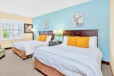 two beds in a room with blue walls and yellow pillows at Apartment with Pool & Hot Tub - Close to Universal Studios in Orlando