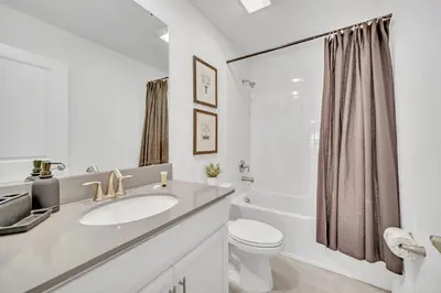 a white bathroom with a sink and a toilet at Perfect 9 Bed 5 Bath Home/Games room/ Private pool in Kissimmee