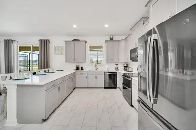 a large kitchen with white cabinets and appliances at Brand New 6BD, Gameroom / Movie Theater And Pool in Kissimmee