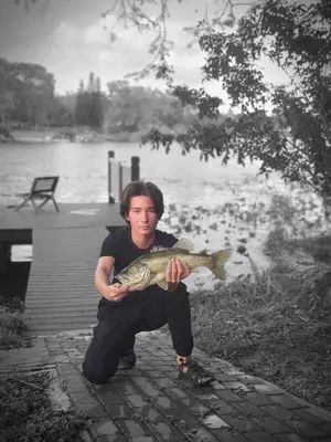 a man holding a fish in front of a body of water at Spring Lake King Balcony Suite in Orlando
