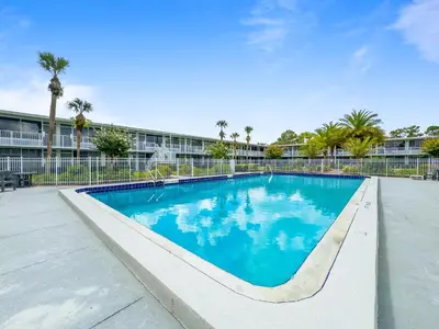 a swimming pool with blue water in front of a building at 15 Mins from Disney World l Theme Room l Pool in Kissimmee