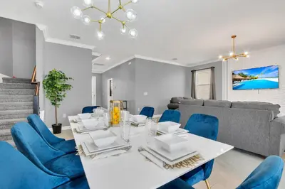 a dining room with a white table and blue chairs at Mickey's Retreat /Pool With Water Slide/ Game Room in Kissimmee