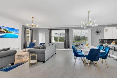 a living room with a table and blue chairs at Mickey's Retreat /Pool With Water Slide/ Game Room in Kissimmee