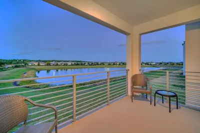 a balcony with two chairs and a view of the water at Stylish 2-Bed Condo With Resort Amenities/Patio in Kissimmee