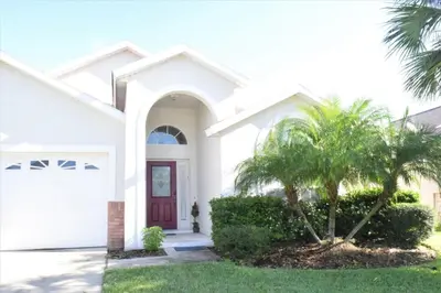 a white house with a palm tree in front of it at 6 bed property - Indian Creek in Kissimmee