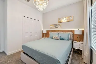 a bedroom with a large bed and a chandelier at 5Q/4B luxuosa casa *Acesso ao Resort* in Kissimmee
