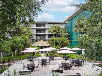 an outdoor patio with tables and chairs and umbrellas at Relaxing 1BR Pirate themed Condo in Orlando Next to Disney with Pool view in Kissimmee