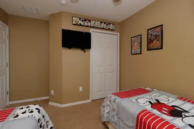 a bedroom with two beds and a flat screen tv at Spacious Emerald Island Resort Home with Pool Spa and Resort Amenities near Disney in Kissimmee