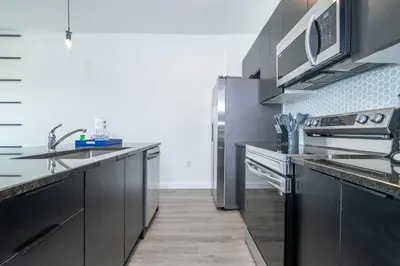 a kitchen with black cabinets and stainless steel appliances at 8761 ZD - Elegant 3BR Villa in The Hub Resort - Comfort, Style, and Luxury for Your Perfect Getaway in Kissimmee