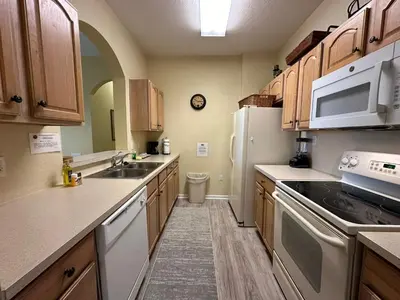a kitchen with wooden cabinets and a white refrigerator at 3Q no Windsor Hills | Perto da Disney + Parque in Orlando