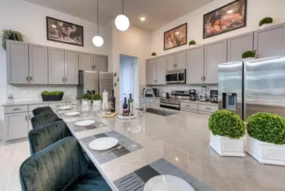 a large kitchen with a long table and chairs at Experience Luxury in Your 11 En-Suites Mansion in Orlando