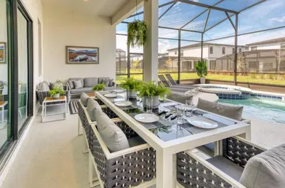 a patio with a table and chairs and a pool at Experience Luxury in Your 11 En-Suites Mansion in Orlando