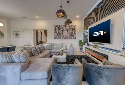 a living room with a couch and a tv at Experience Luxury in Your 11 En-Suites Mansion in Orlando