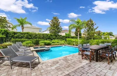 a patio with a table and chairs next to a pool at Charming Home Near Disney With Private Pool, Game Room And Waterpark & Resort Access At Encore Resorts Reunion - 410No in Kissimmee