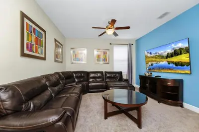 a living room with a leather couch and a flat screen tv at Charming Home Near Disney With Private Pool, Game Room And Waterpark & Resort Access At Encore Resorts Reunion - 410No in Kissimmee