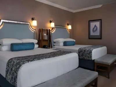 a hotel room with two beds and a bench at Disney's Beach Club Resort in Orlando