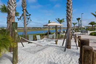 a hammock on the beach with palm trees at Luxuosa Casa 4Q/3B Storey Lake in Kissimmee