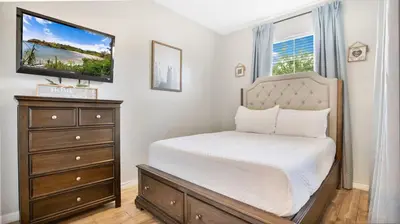 a bedroom with a bed and a dresser with a television at Family Friendly Townhome Near Attractions in Orlando