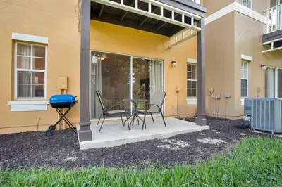 a patio with two chairs and a grill next to a building at Relaxing Getaway in Emerald Island Near Disney in Kissimmee