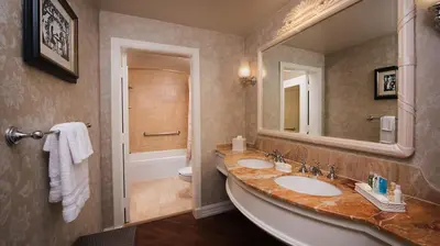 a bathroom with two sinks and a toilet and a mirror at Disney's Grand Floridian Resort And Spa in Orlando