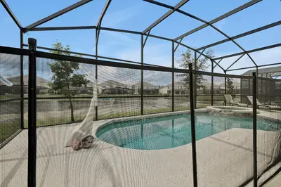 a hammock in a greenhouse next to a swimming pool at Luxury 12-BR Villa w/ Pool & Resort Amenities Near Disney in Kissimmee