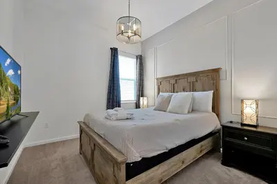 a bedroom with a large bed and a television at Luxury 12-BR Villa w/ Pool & Resort Amenities Near Disney in Kissimmee