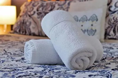 a roll of white towels sitting on a bed at Waterfront Villa showcasing a theater, games room, and a private pool in Kissimmee