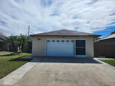 a house with a blue garage door in a driveway at 3Q/2B Perto da DISNEY, Piscina Privativa in Kissimmee
