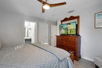 a bedroom with a bed and a dresser with a flat screen tv at Six Bedroom Disney Home Lanai Screened Pool & Spa villa in Kissimmee